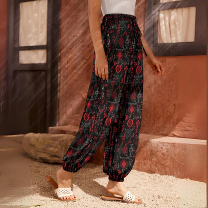 Flowy black harem pants with red floral print pattern and elastic cuffs at the ankles, side view - MYSTICAL SYMBOLS BLACK HAREM PANTS WOMEN FOR YOGA PRACTICE