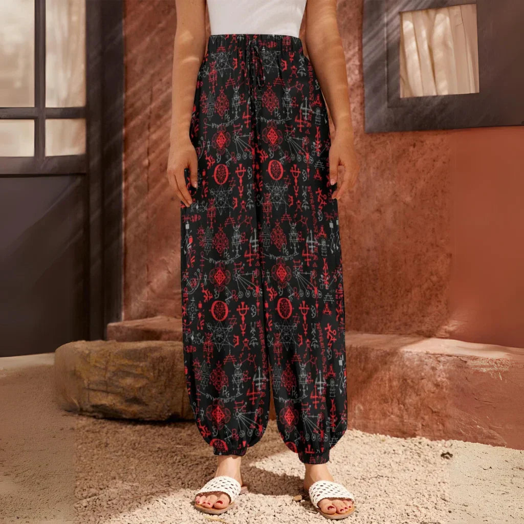 Flowy black harem pants with red floral print pattern and elastic cuffs at the ankles, front view - MYSTICAL SYMBOLS BLACK HAREM PANTS WOMEN FOR YOGA PRACTICE