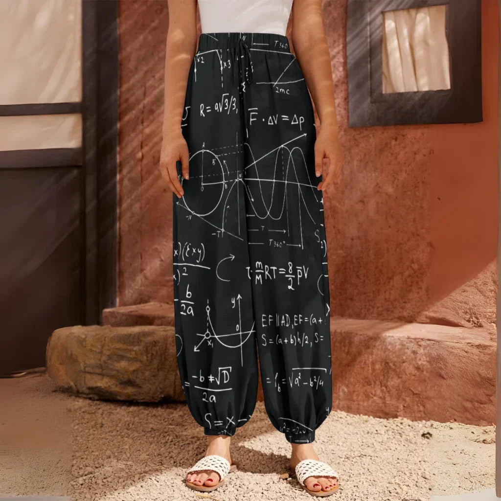 Black pants with white mathematical equations and formulas printed all over them, front view - SEAMLESS MATH FORMULA HAREM PANTS WOMEN WITH DIVINE DESIGN