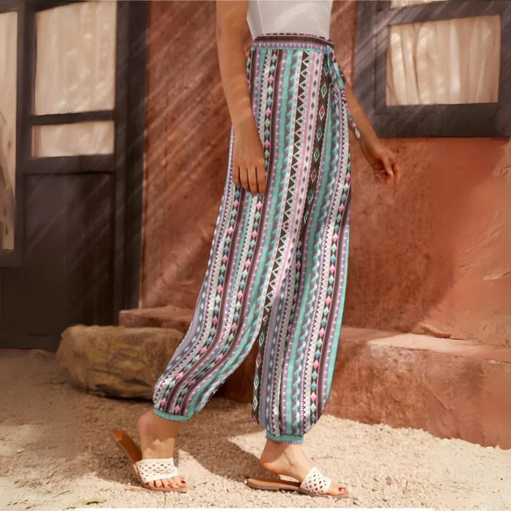 Loose-fitting patterned pants with vertical stripes in turquoise, red, and white, side view - VIBRANT BOHEMIAN STRIPED HAREM PANTS WOMEN